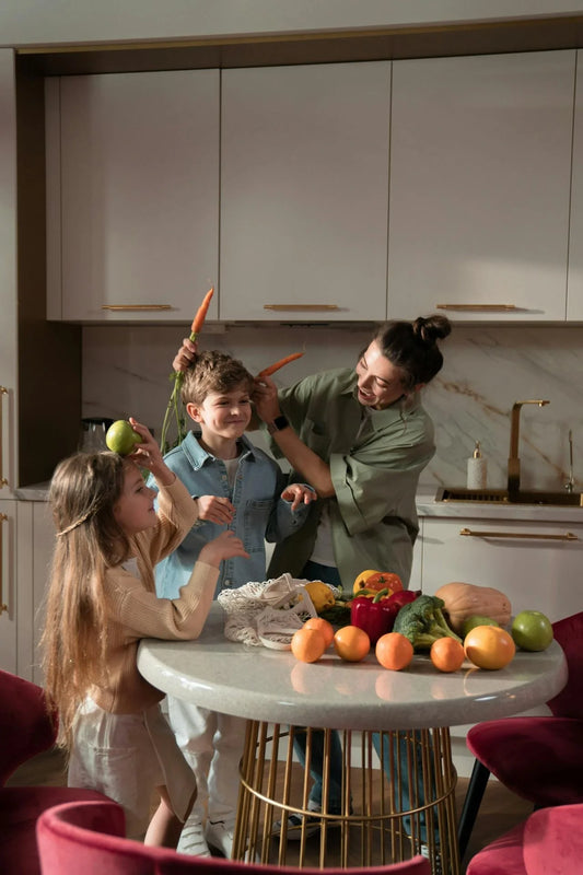 A mum and 2 children in the kitchen with fruit and vegtables