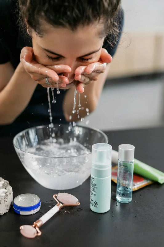 A woman practicing her skincare routine with a face wash and products on a counter