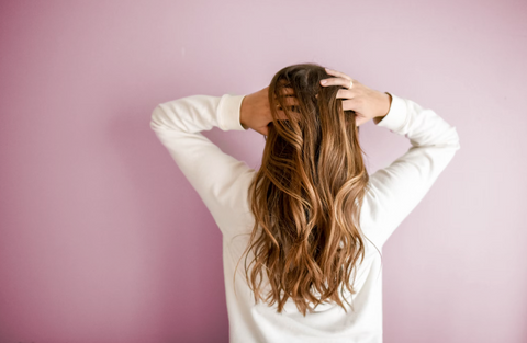Back of woman's head with long hair and hands on hair
