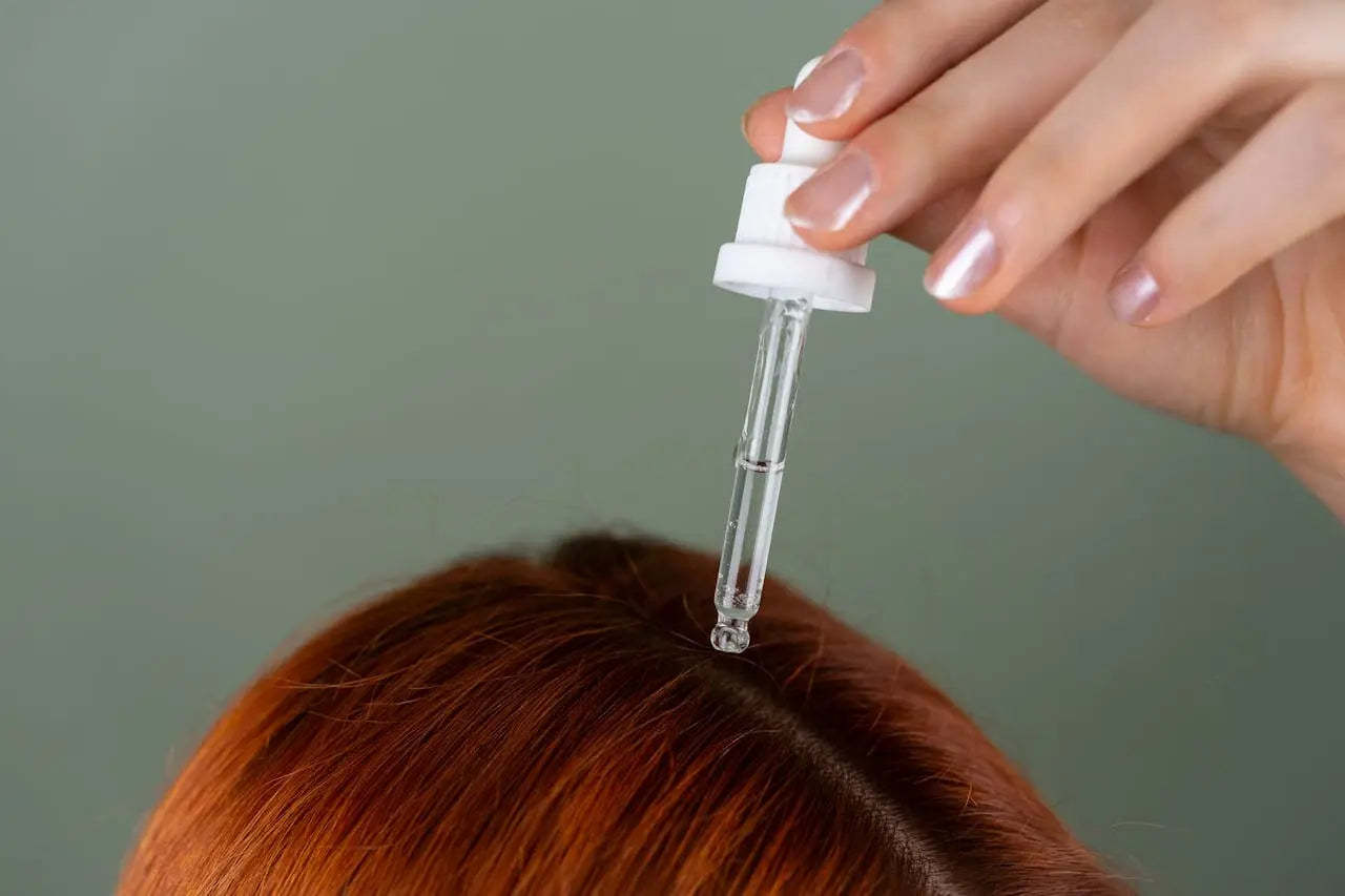 A woman squeezing supplements from a pipette onto her hair