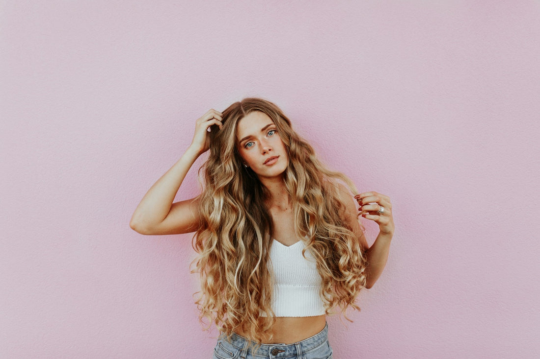Women showcasing her healthy hair on a pink background