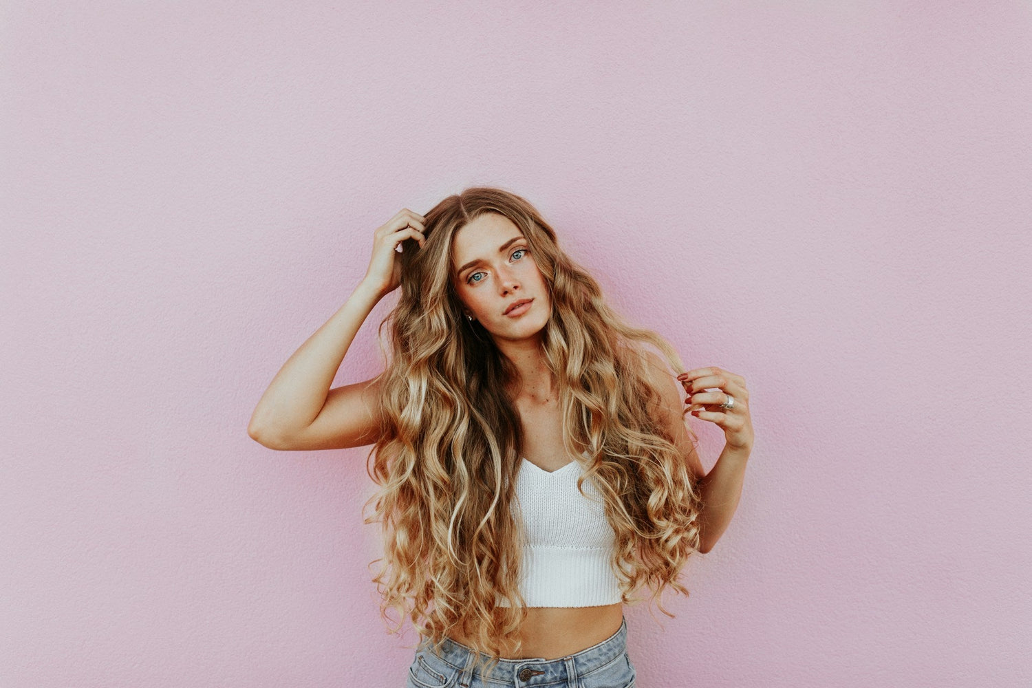 Women showcasing her healthy hair on a pink background